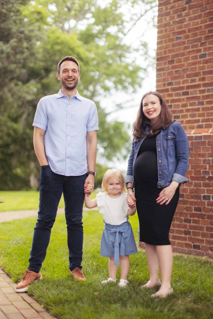 A family poses for a portrait in front of a brick building.