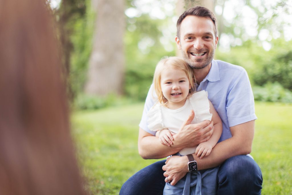 A man is holding a little girl in a family portrait.