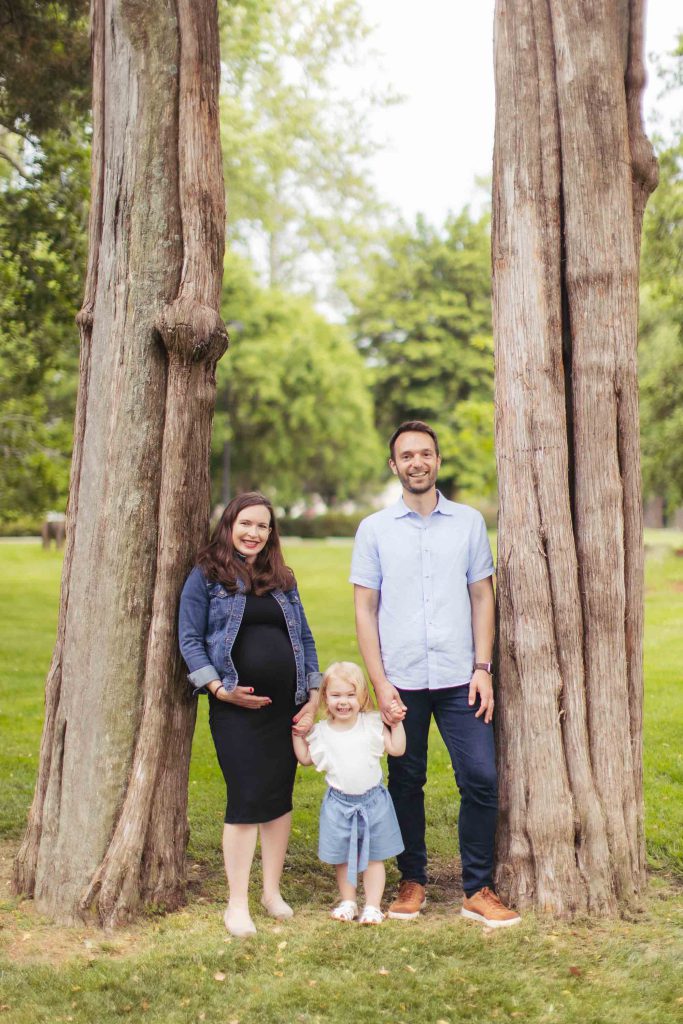 A family poses in front of a tree.