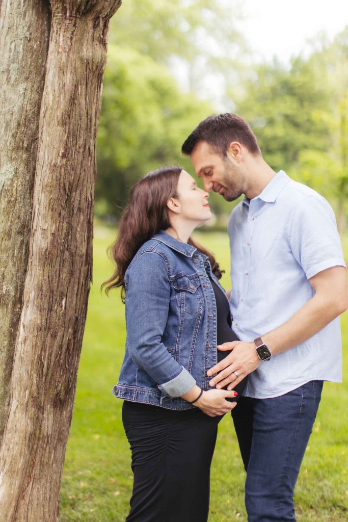 A pregnant woman, man, and family sharing intimate portraits in a park near their Bel Air Mansion.