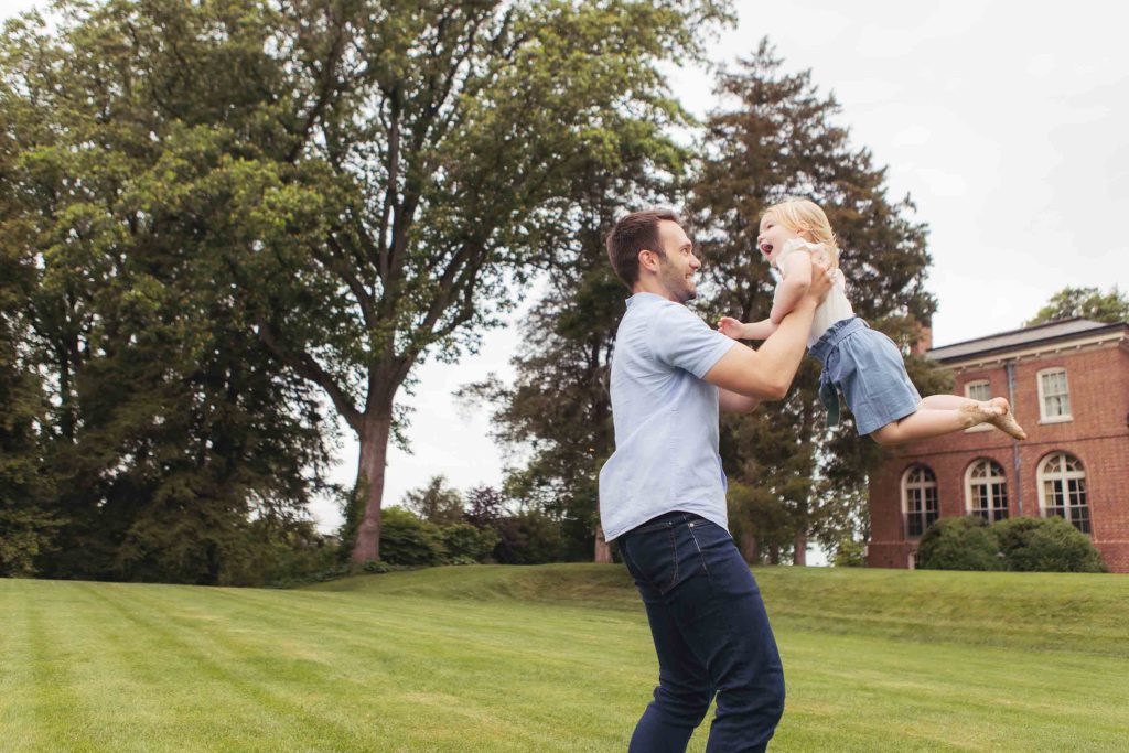A family playing in the grass in front of a large house.