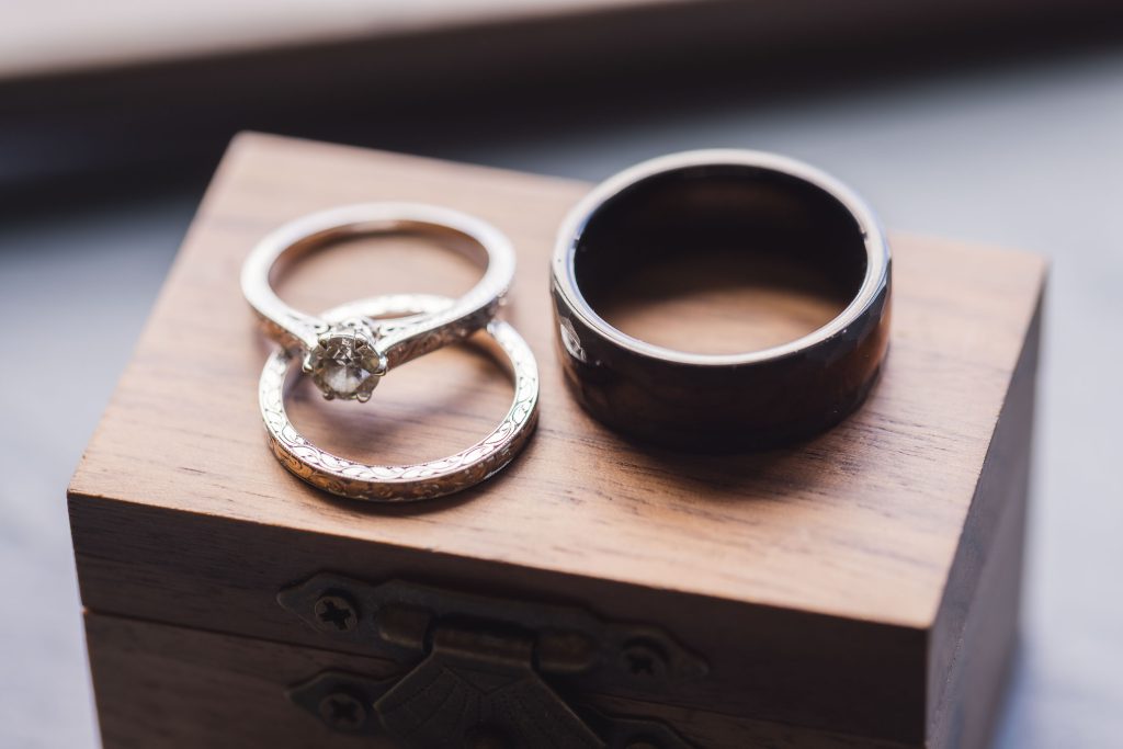 A detailed wedding ring atop a wooden box.