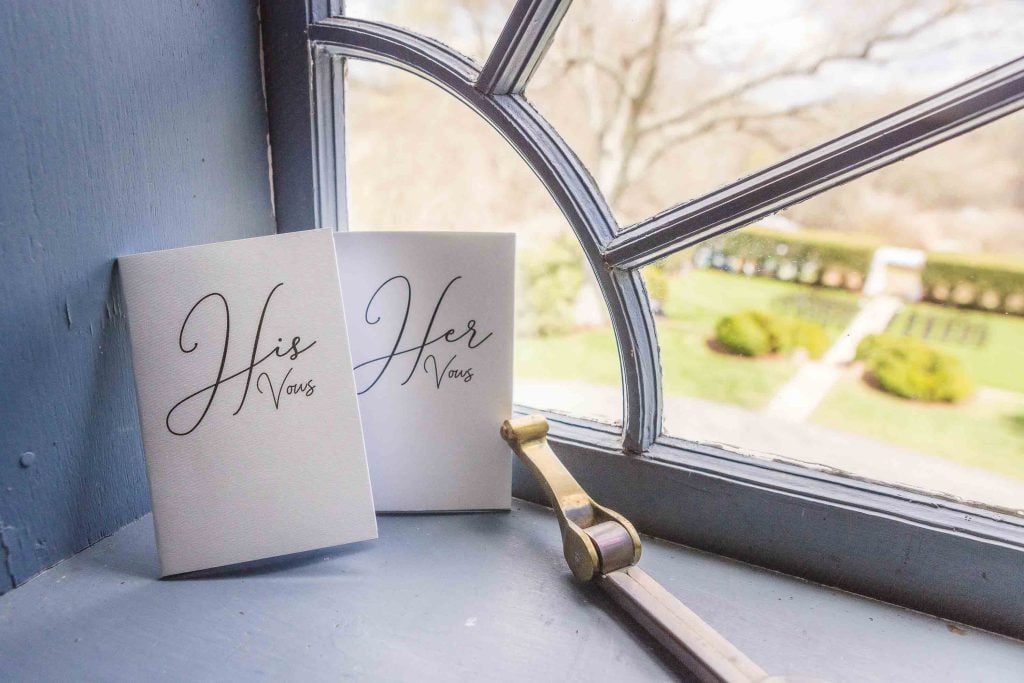 Two wedding invitations displayed on a window sill, showcasing intricate details.