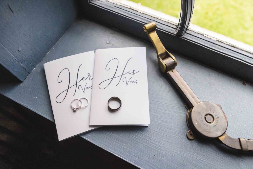 A detailed window sill displaying a pair of wedding rings and a book.