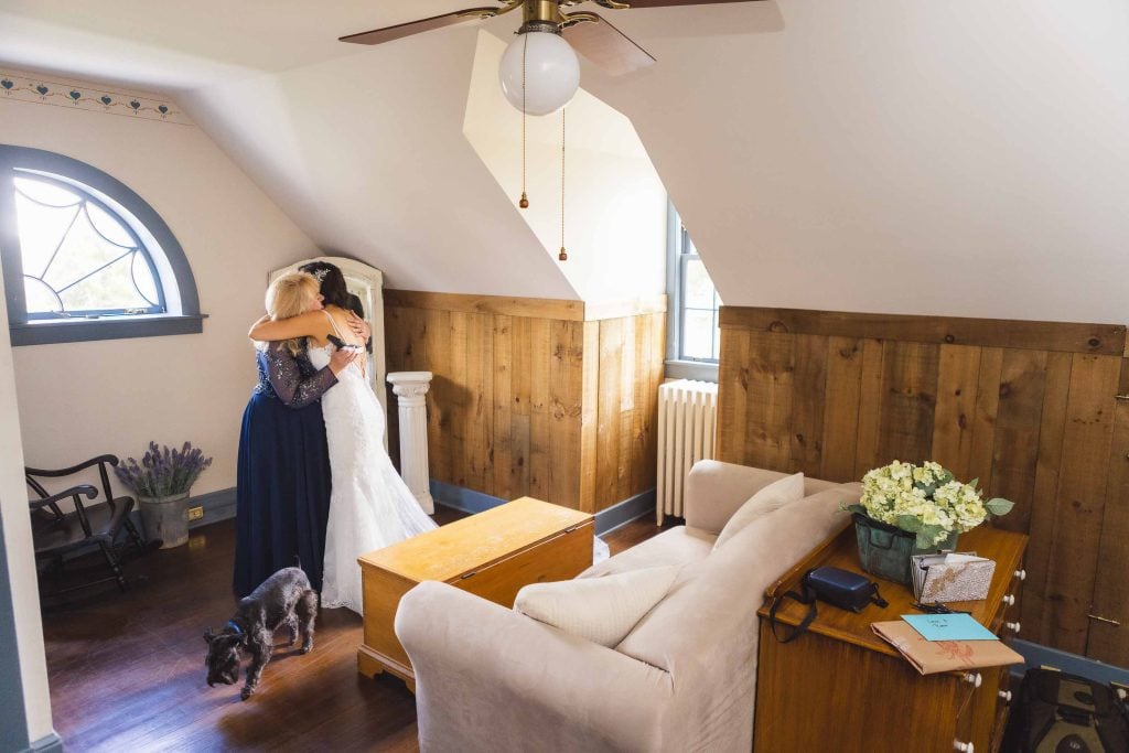 A bride is hugging her bridesmaid in a candid moment during wedding preparation.