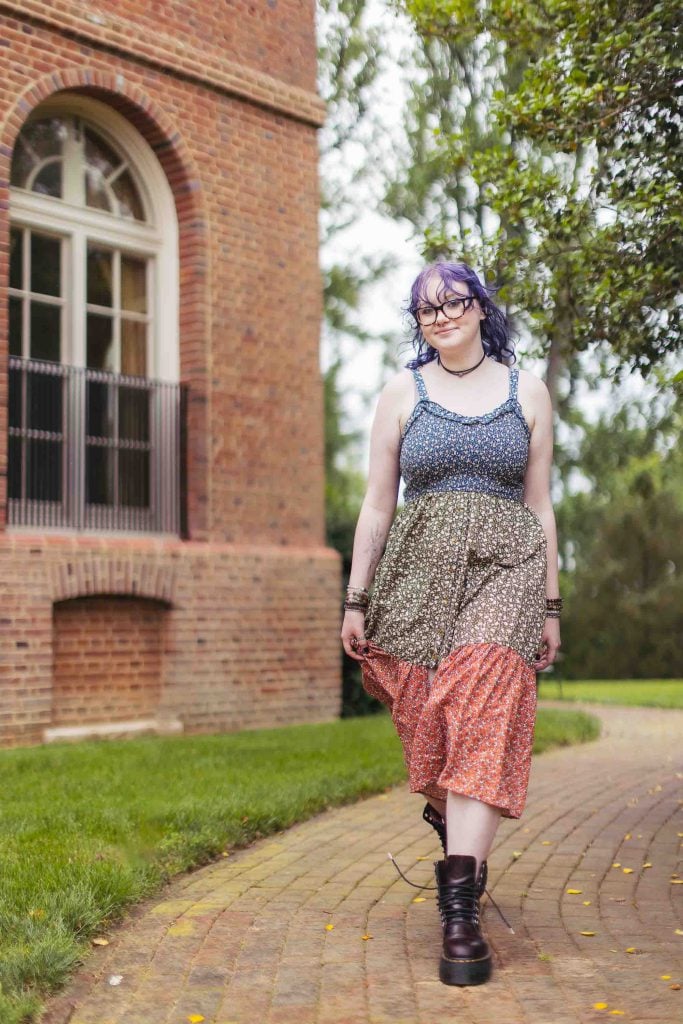 A woman with purple hair walking down a brick path at a Bel Air Mansion.