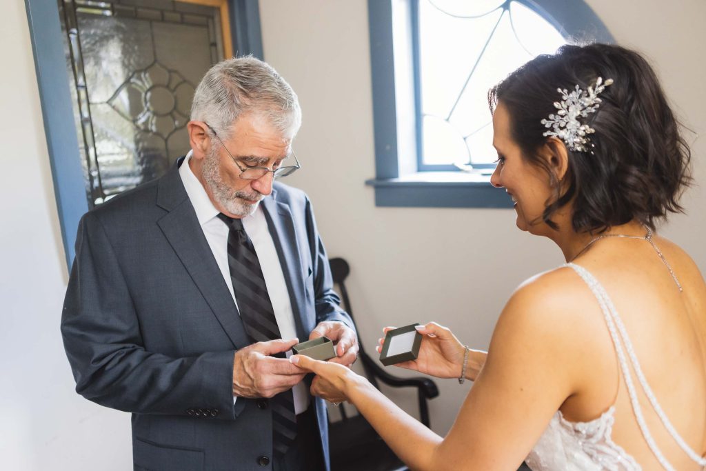 Preparation: A woman is placing her wedding ring on a man's finger during their preparation for the wedding.