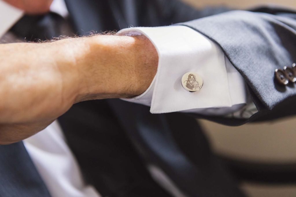 A man in a suit is adjusting his cufflinks for a wedding.