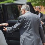 A candid wedding preparation moment: A bride and groom emerging from a black limo.