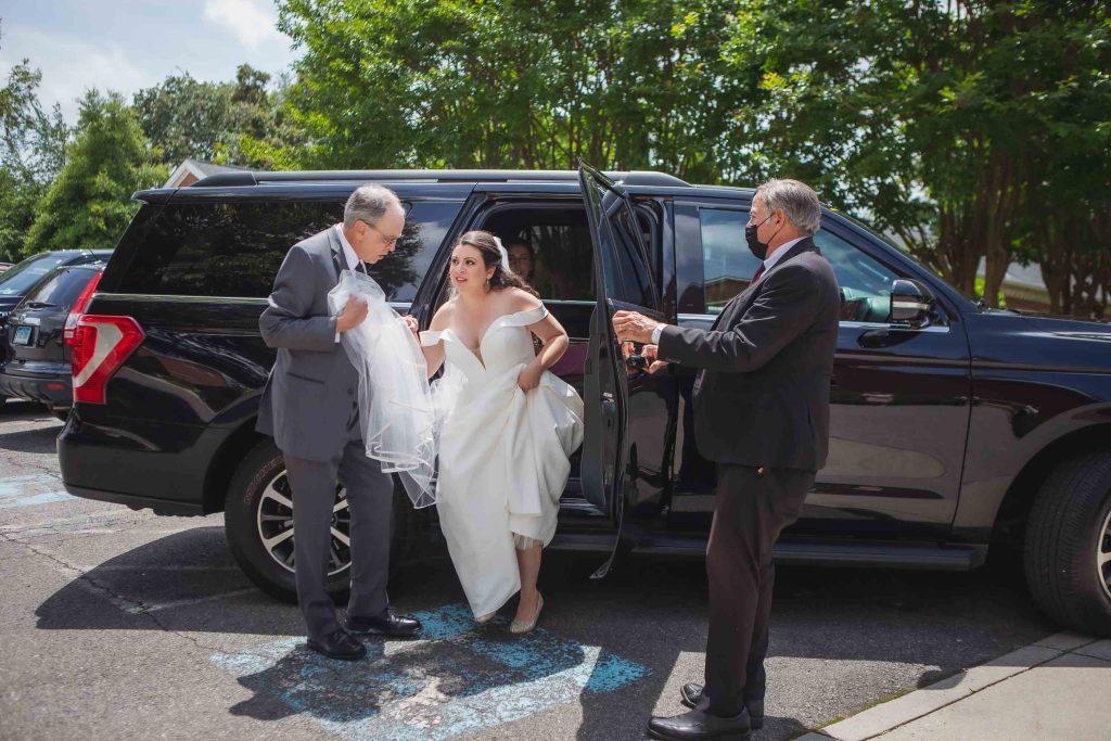 A candid bride and groom preparing for their wedding, getting out of a black suv.