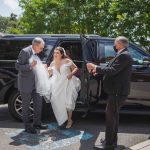 A candid bride and groom preparing for their wedding, getting out of a black suv.