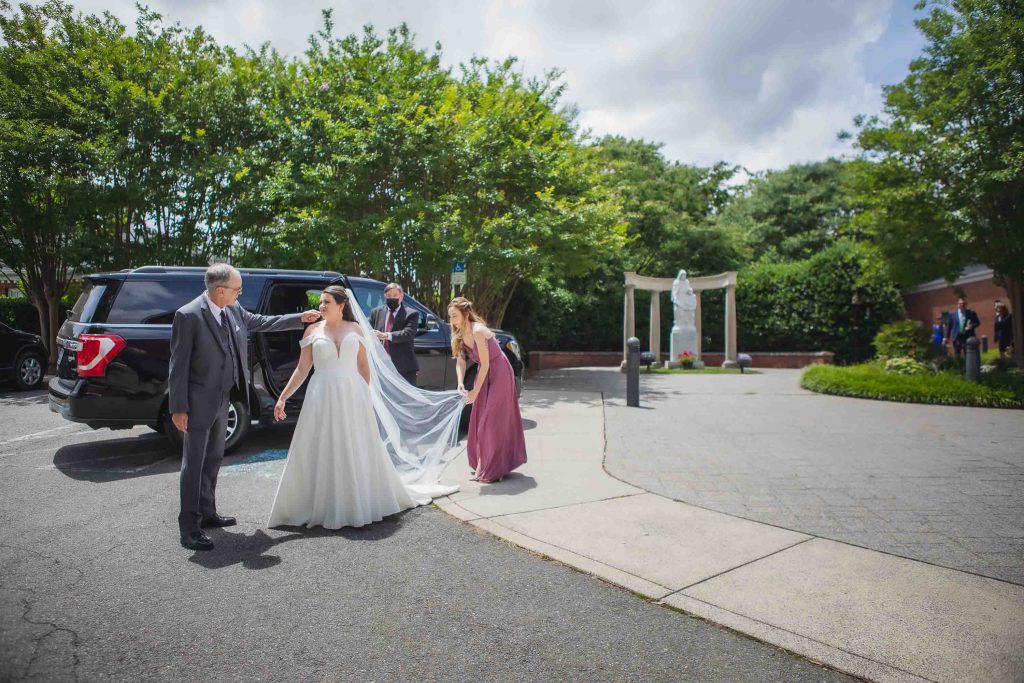 A candid bride and groom walking to their car in front of a church after the wedding preparations.
