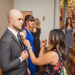 A man is candidly preparing a boutonniere for a wedding ceremony in a church.