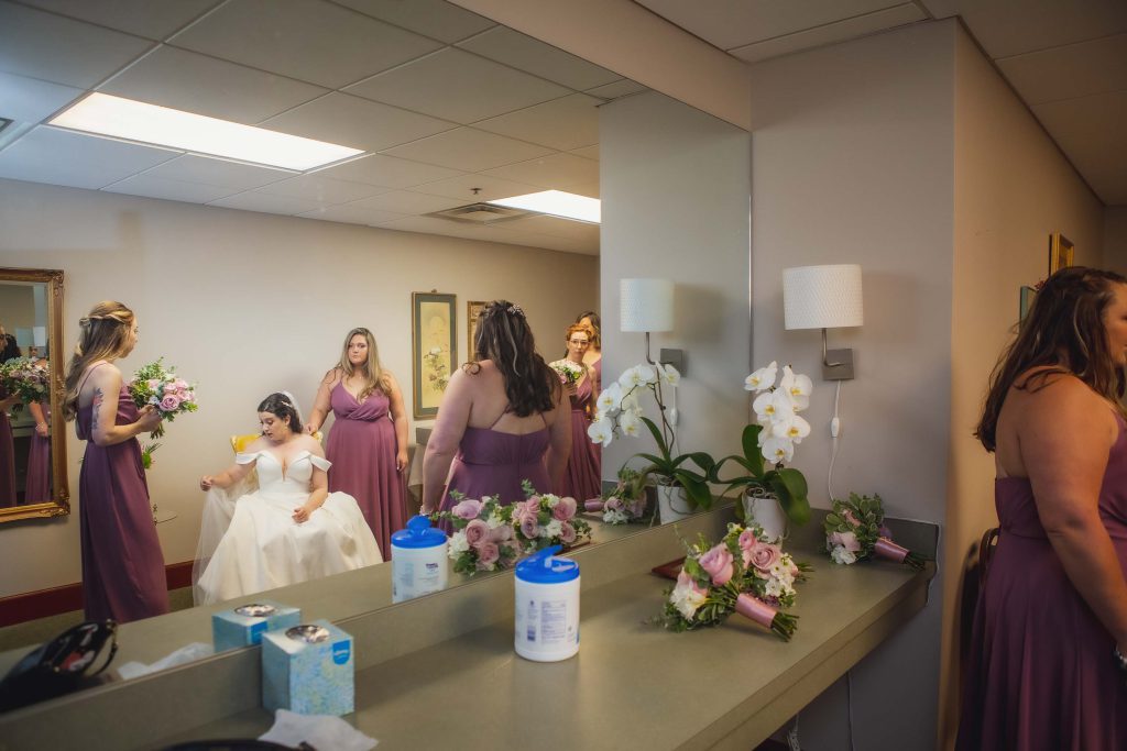 Bridesmaids candidly preparing for wedding in a mirror.