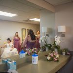 Bridesmaids candidly preparing for wedding in a mirror.