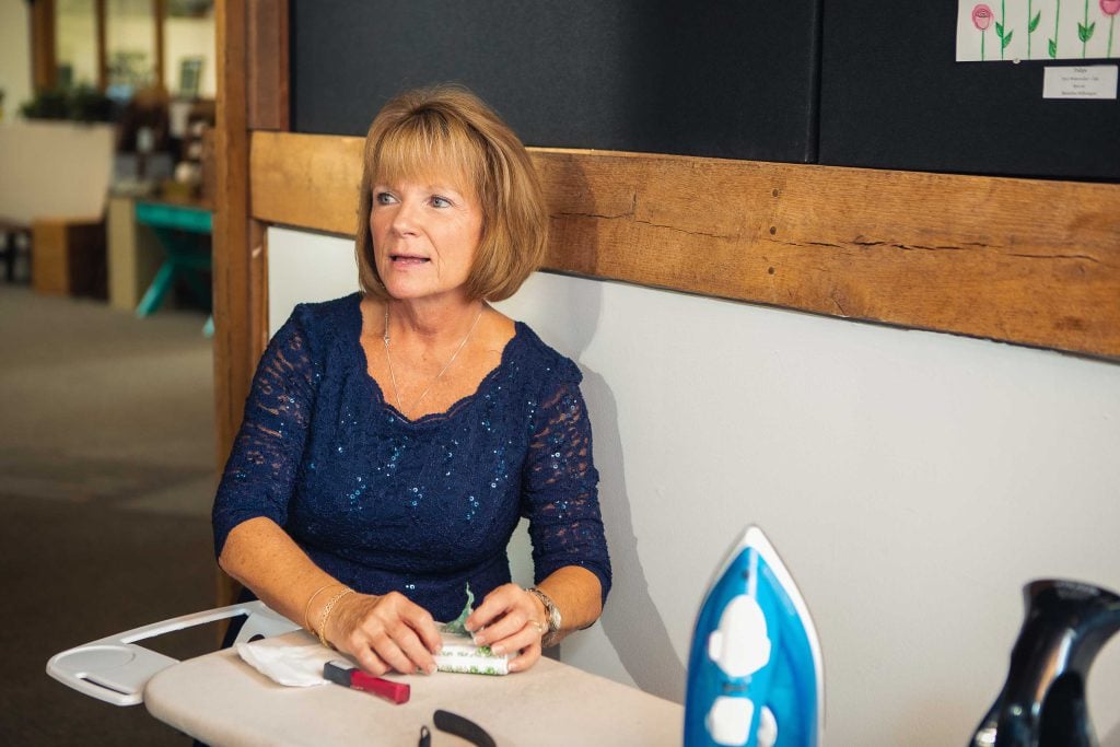 A candid woman preparing for a wedding at an ironing board.