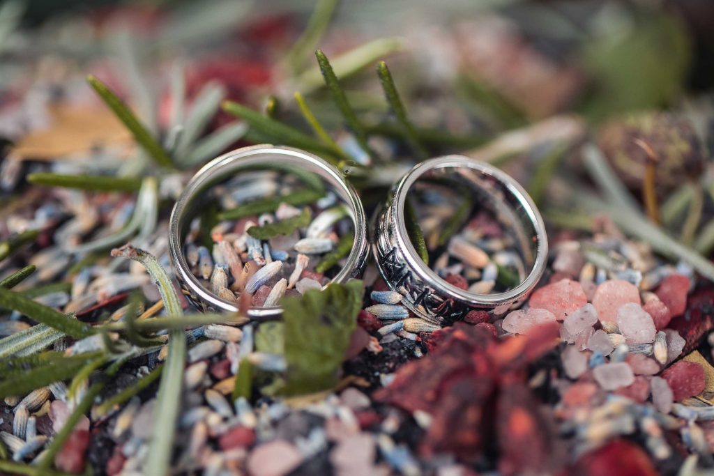 Two stacked wedding rings on rocks, showcasing intricate details.
