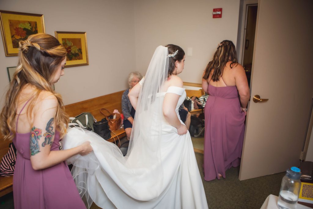 A bride is preparing for her wedding surrounded by bridesmaids.