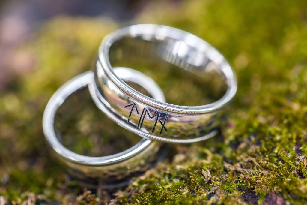 Two wedding rings resting atop moss.
