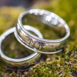 Two wedding rings resting atop moss.