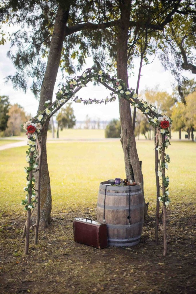 A detailed wooden arch decorated with flowers for a wedding ceremony.