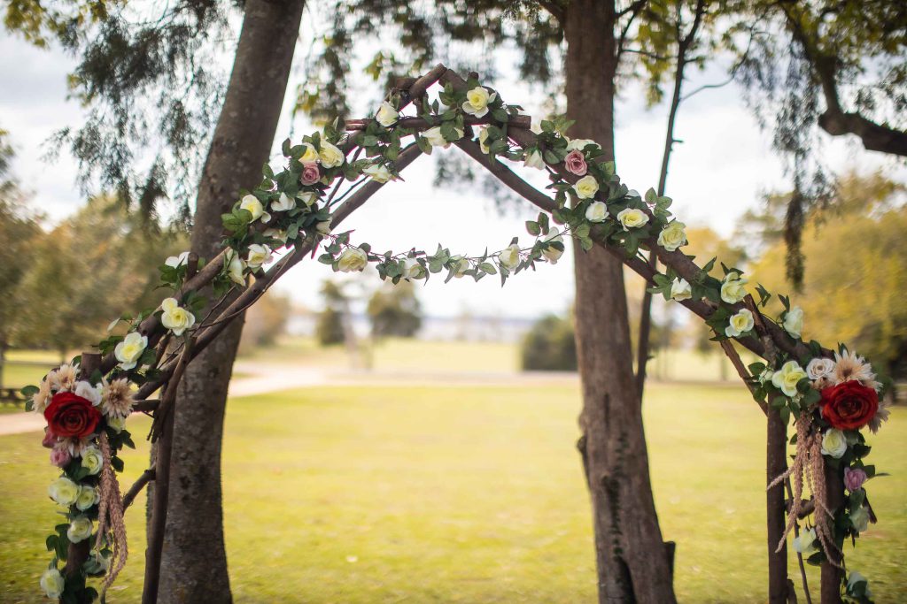 A detailed wedding arch adorned with flowers and twigs.