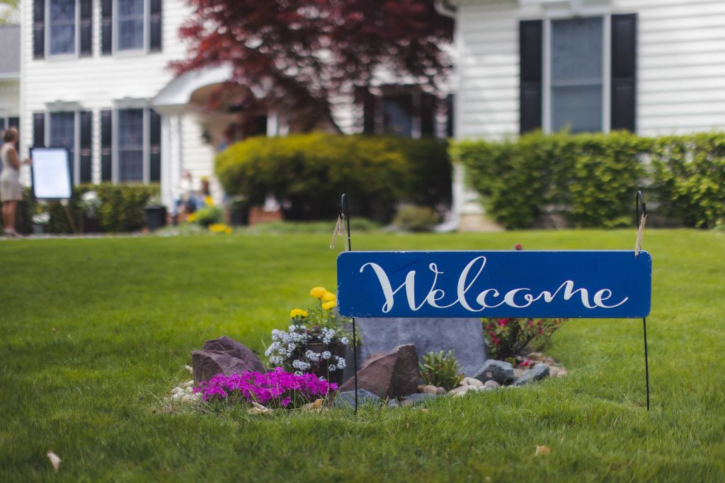 A welcome sign with wedding details in front of a house.