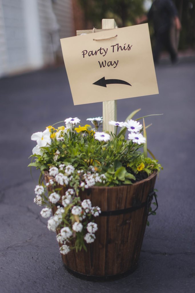 A wedding centerpiece with flowers in a wooden bucket.