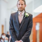 A man in a suit standing at a wedding ceremony in a church.