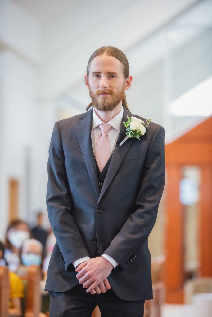 A man in a suit standing at a wedding ceremony in a church.