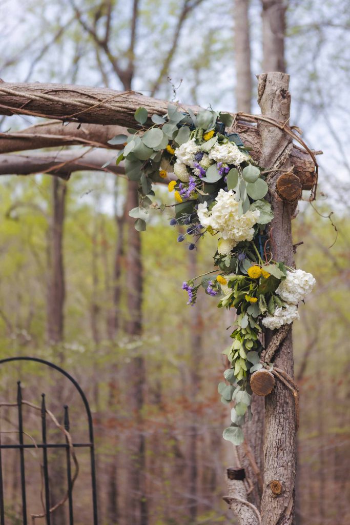 A wedding arch adorned with flowers in the woods.
