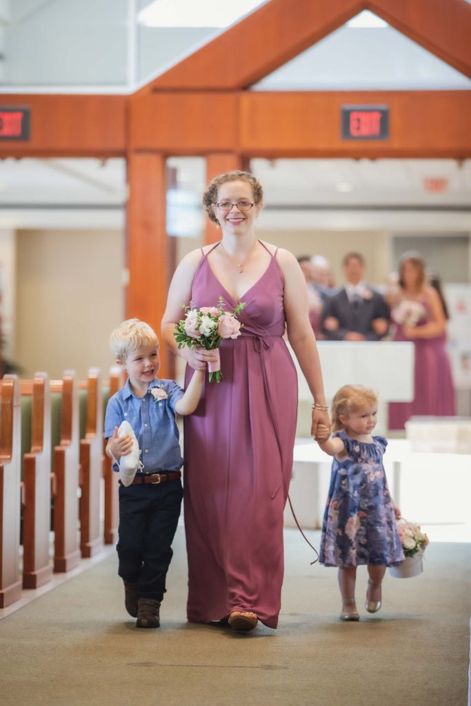 A woman and her children walking down the aisle of a church during a wedding ceremony.