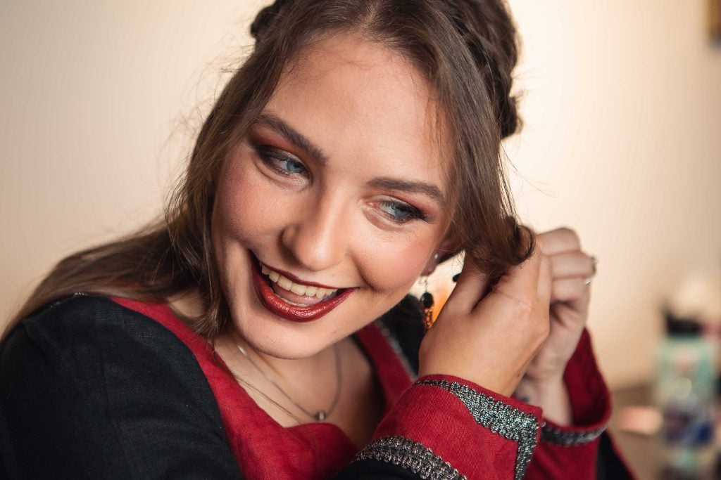 A woman is candidly smiling while preparing for a wedding.