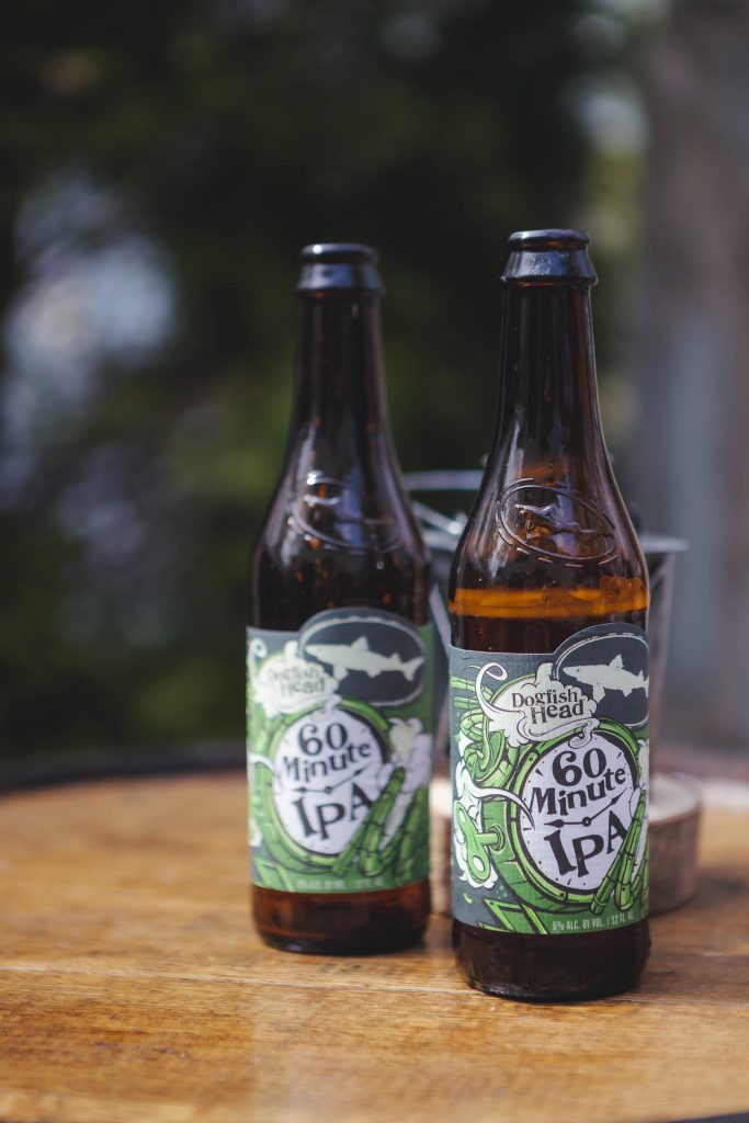 Two bottles of beer sitting on a wooden table, capturing the wedding details.