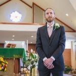 A man in a suit standing in front of a wedding ceremony venue.