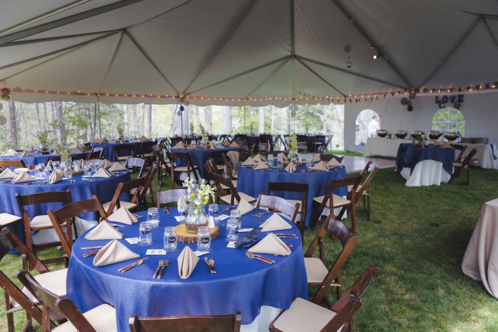 A detailed wedding reception featuring tables and chairs set up in a tent.