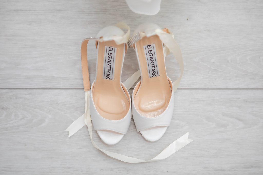 A pair of white shoes with intricate bow details perfect for a wedding.