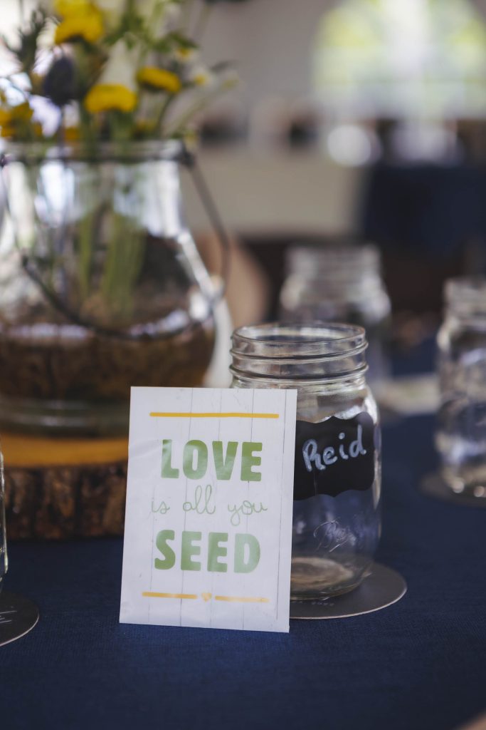 A wedding table with decorative jars and a sign that says love kills you seed.
