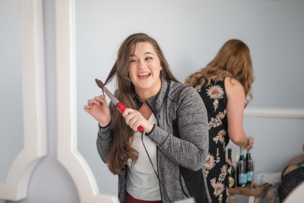 A woman is brushing her hair in front of a mirror while preparing for a wedding.