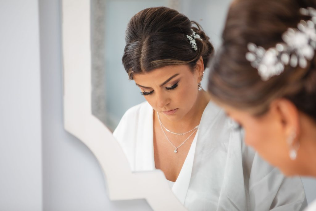A bride prepares for her wedding day as she admires herself in front of a mirror.