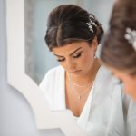 A bride prepares for her wedding day as she admires herself in front of a mirror.