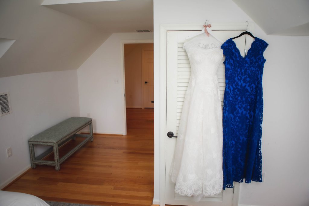 A detailed wedding dress hanging in a closet.