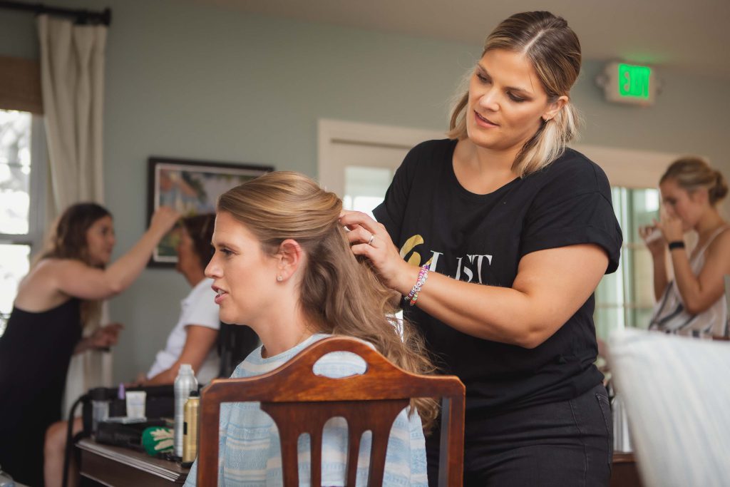 A candid woman getting her hair done in preparation for a wedding.