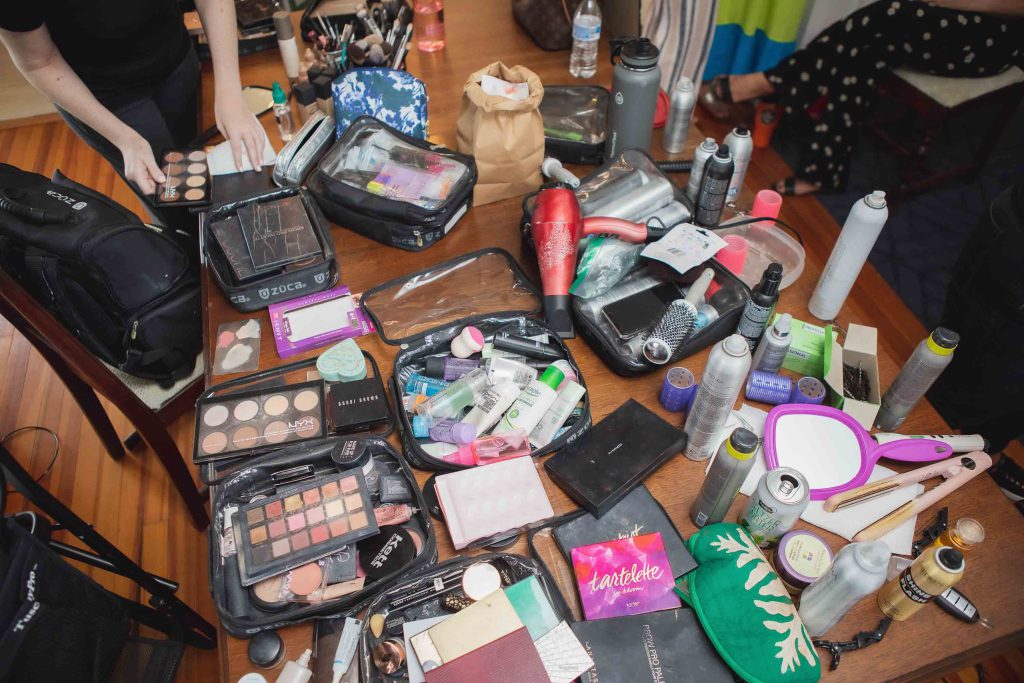 A table with a lot of candid makeup items for wedding preparation.