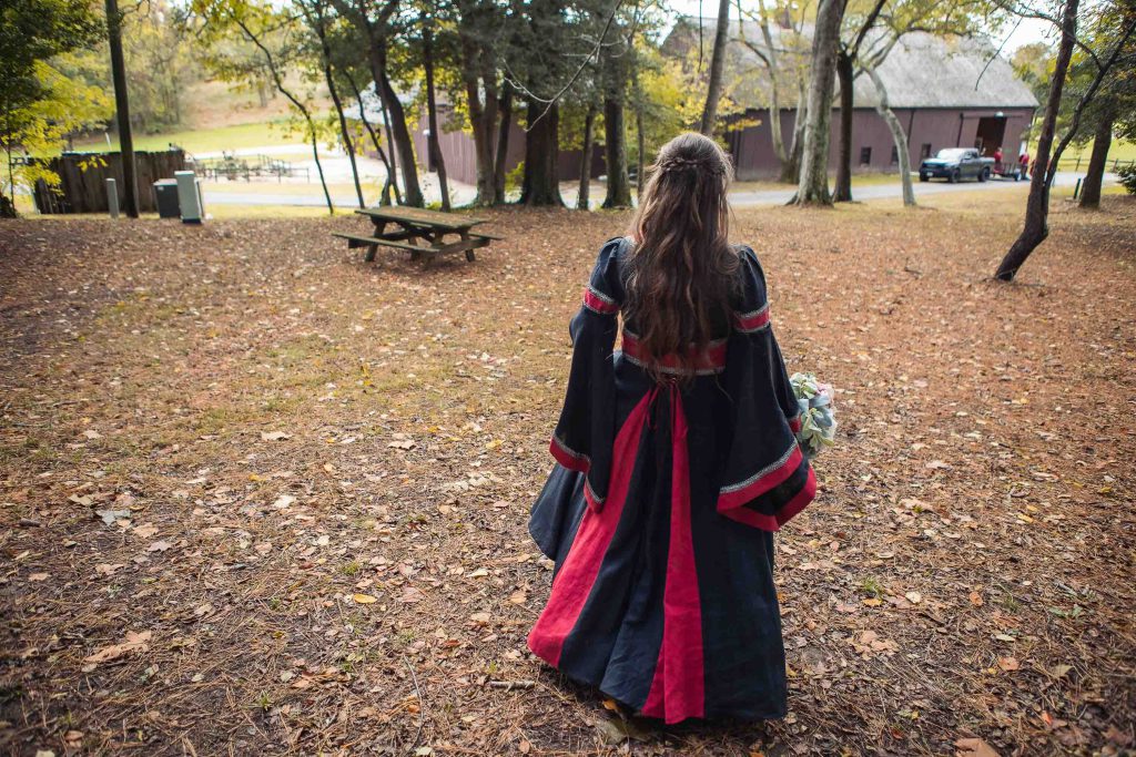 A candid bride in a medieval costume preparing for her wedding in the woods.