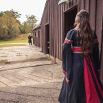 A woman in a viking dress is standing in front of a barn, preparing for her candid wedding.