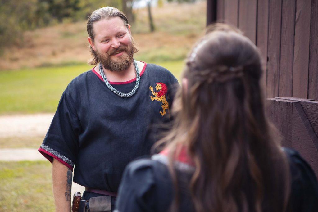 A man in a medieval costume is candidly preparing for a wedding conversation with a woman.