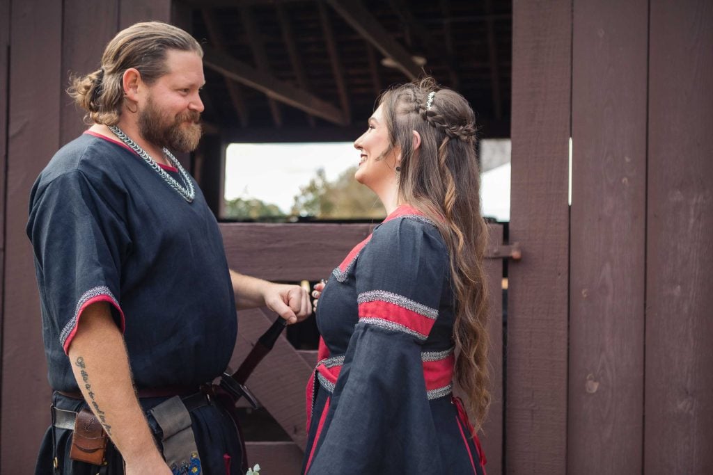 A wedding couple dressed in viking costumes are standing next to each other.