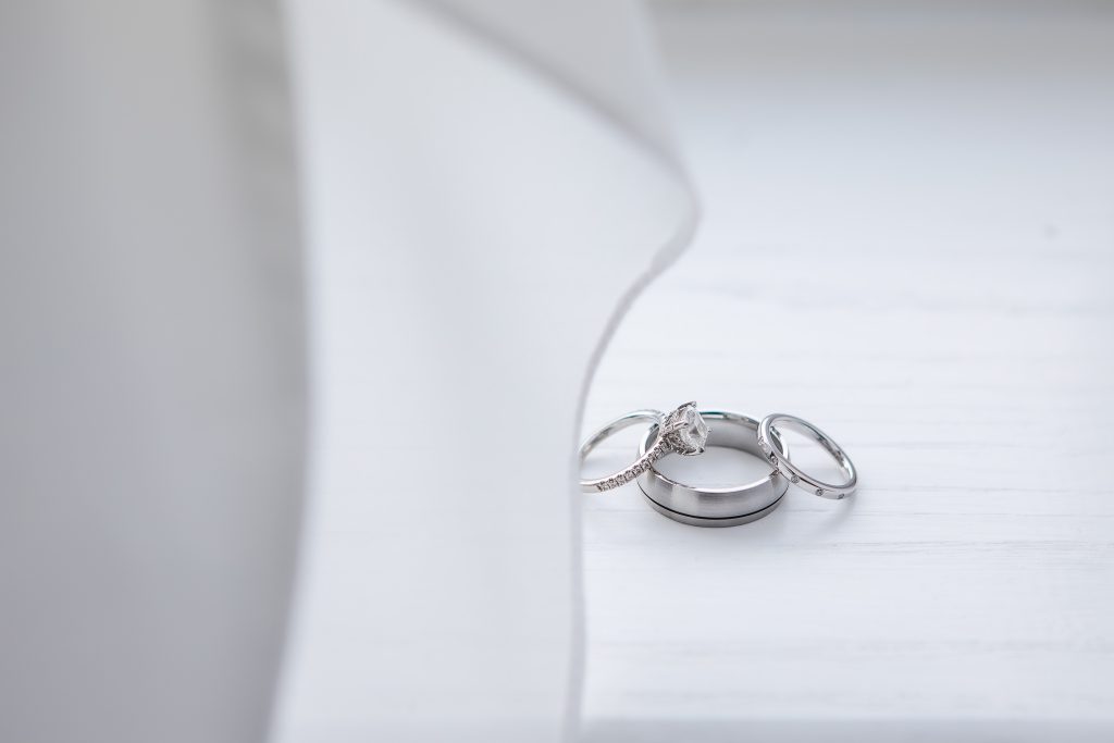 Wedding rings on a white table, showcasing intricate details.