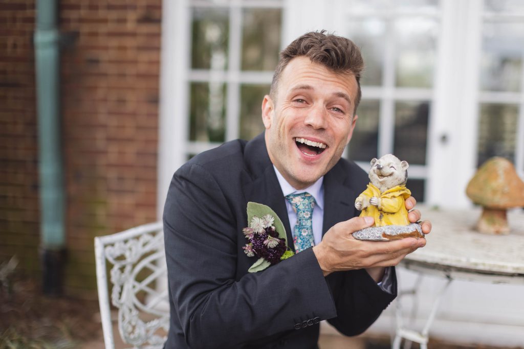 A man in a suit is holding a figurine of a teddy bear in this portrait.